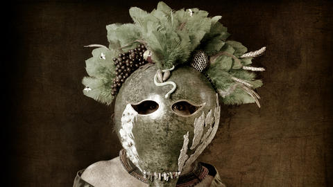 Figure holding a metal mask with feathers on top