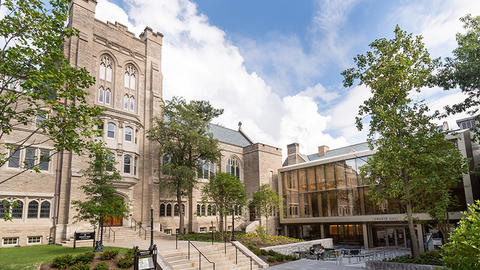 Renovated Swartz Hall, showing both the gray stone building 's tower and the newer modern glass section with the main entrance